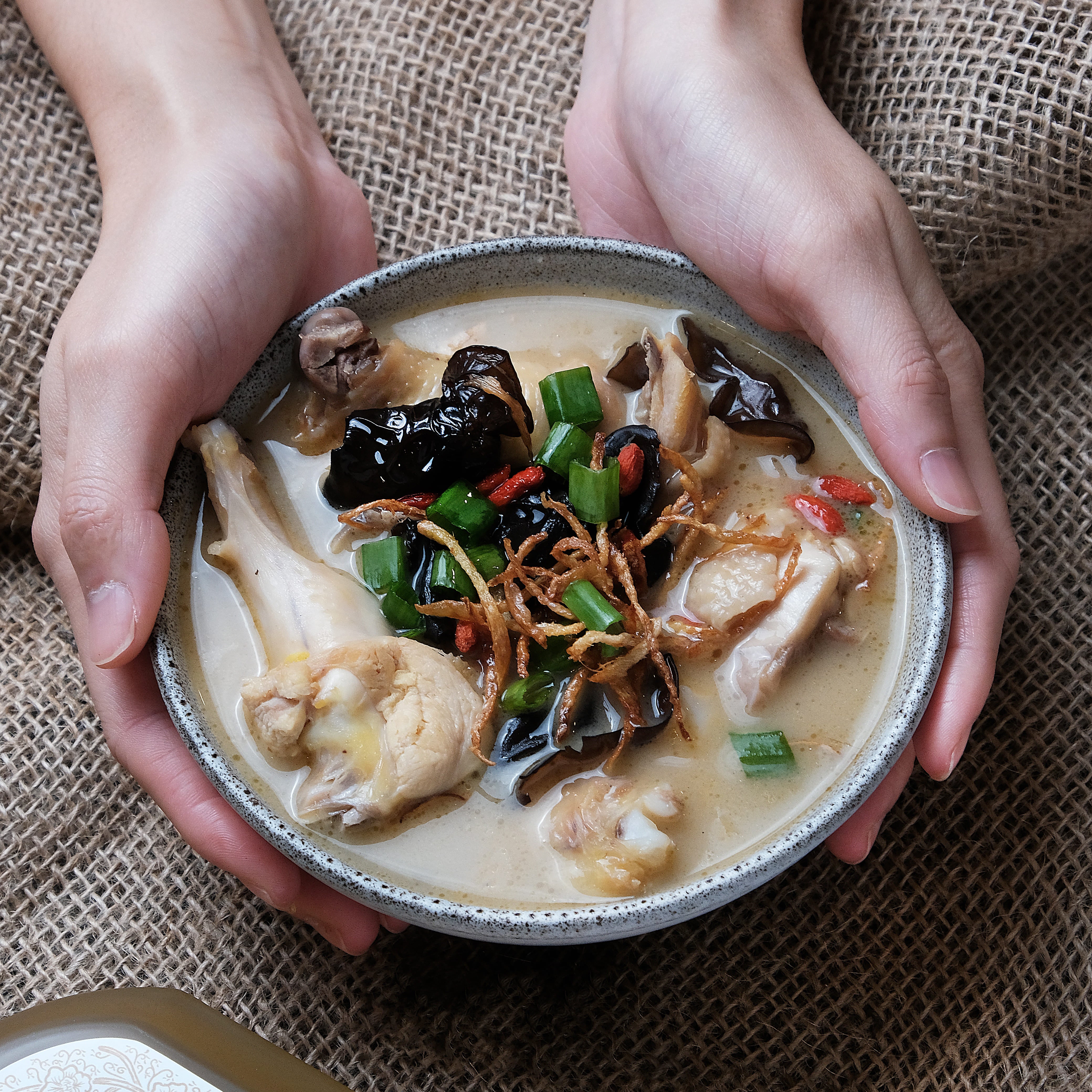 hand holding bowl of hakka chinese wine chicken soup
